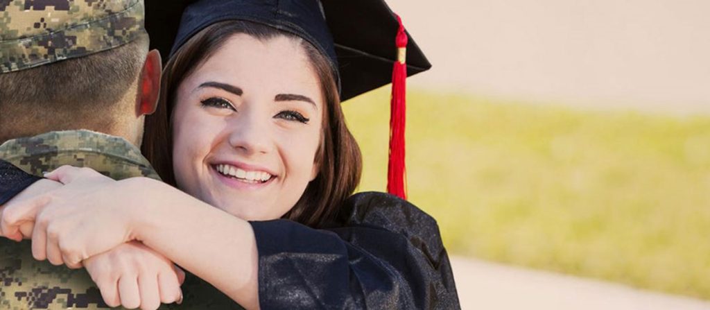 Teenage girl  wearing graduation gown hugging loved one in military uniform